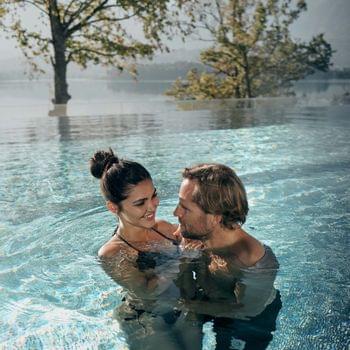 36 ore al Karnerhof Coppia sorridente che si gode un momento romantico in piscina a sfioro con vista lago